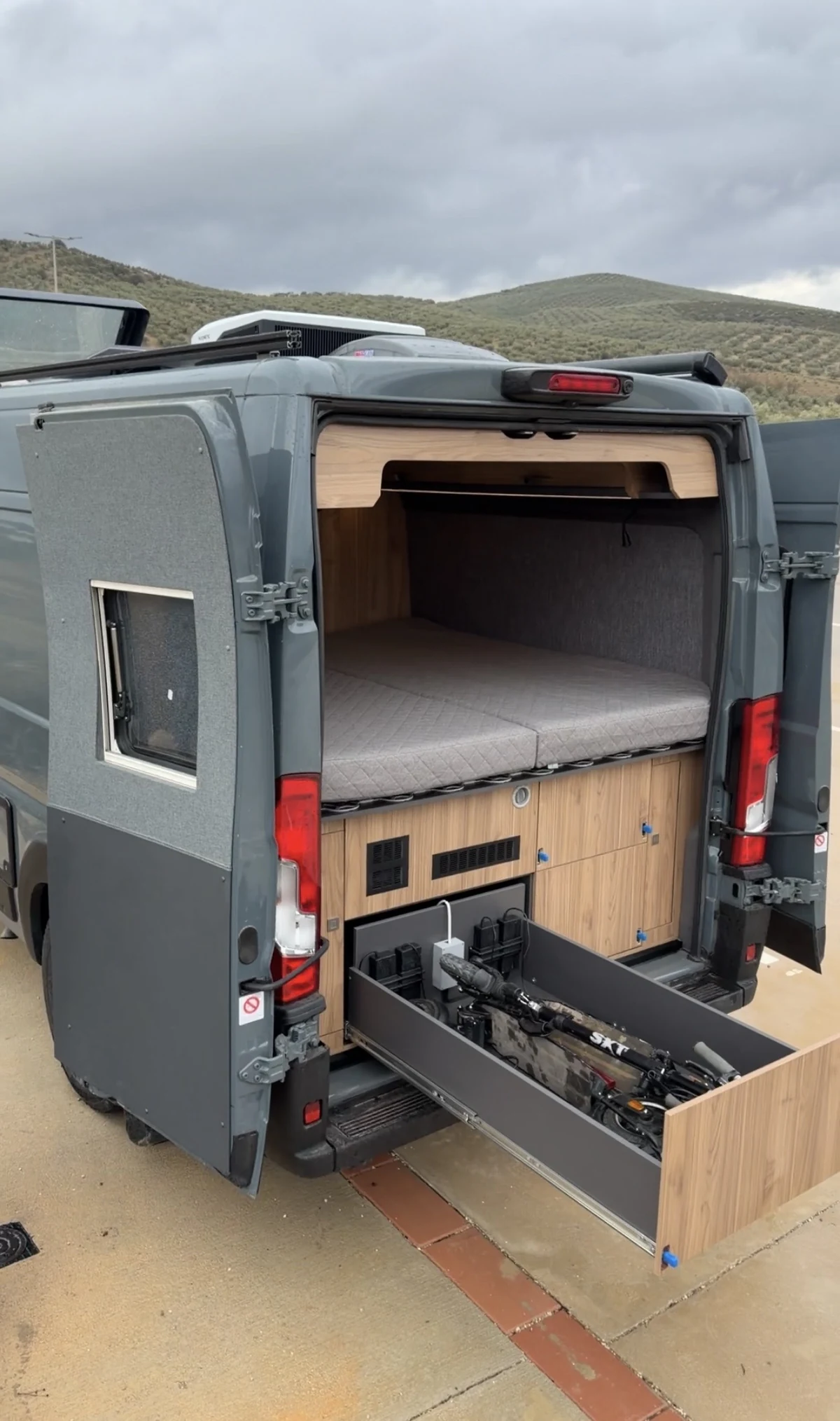 Pull-out bicycle storage drawer beneath the rear bed in a BeBrightCamp campervan